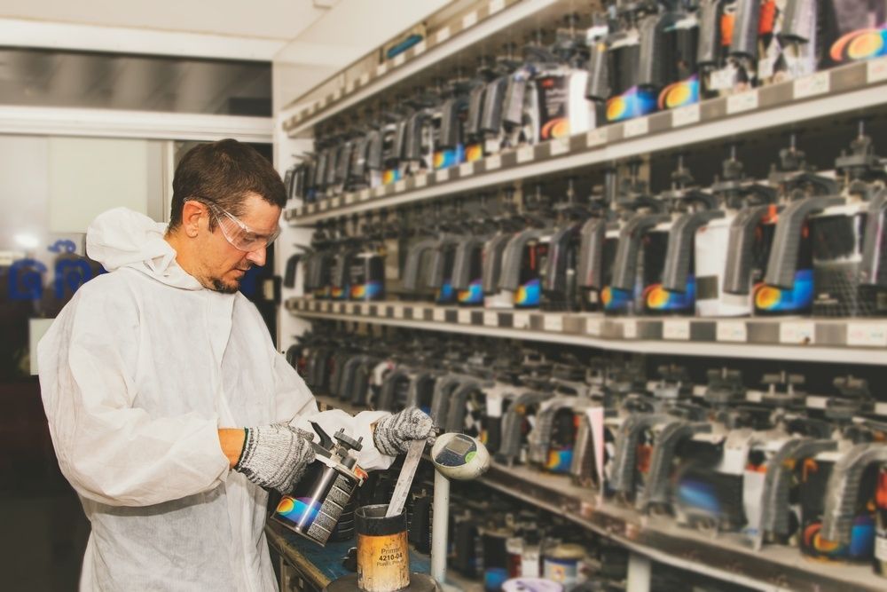 A Man In A White Suit Is Working In A Paint Booth — JA Toft & Co In Bundaberg Central, QLD