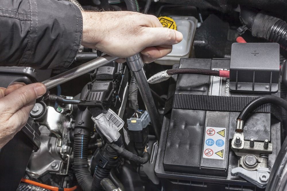 A Person Is Working On A Car Battery With A Wrench — JA Toft & Co In Bundaberg Central, QLD
