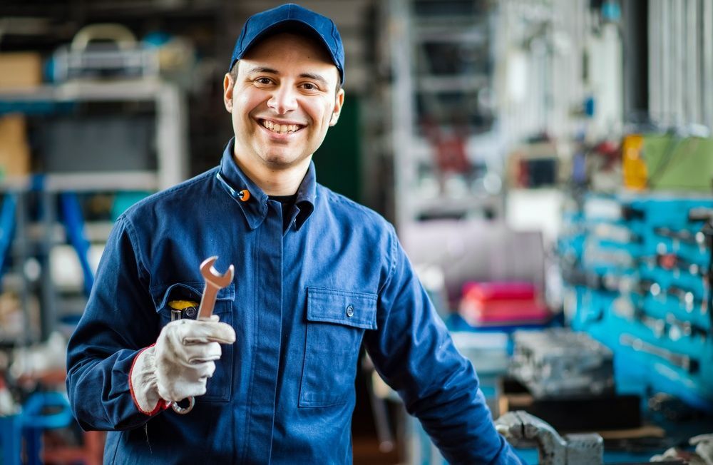 A Smiling Mechanic Is Holding a Wrench — JA Toft & Co In Bundaberg Central, QLD