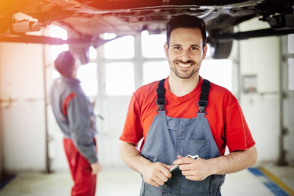 A Man Is Standing In Front Of A Car In A Garage — JA Toft & Co In Bundaberg Central, QLD
