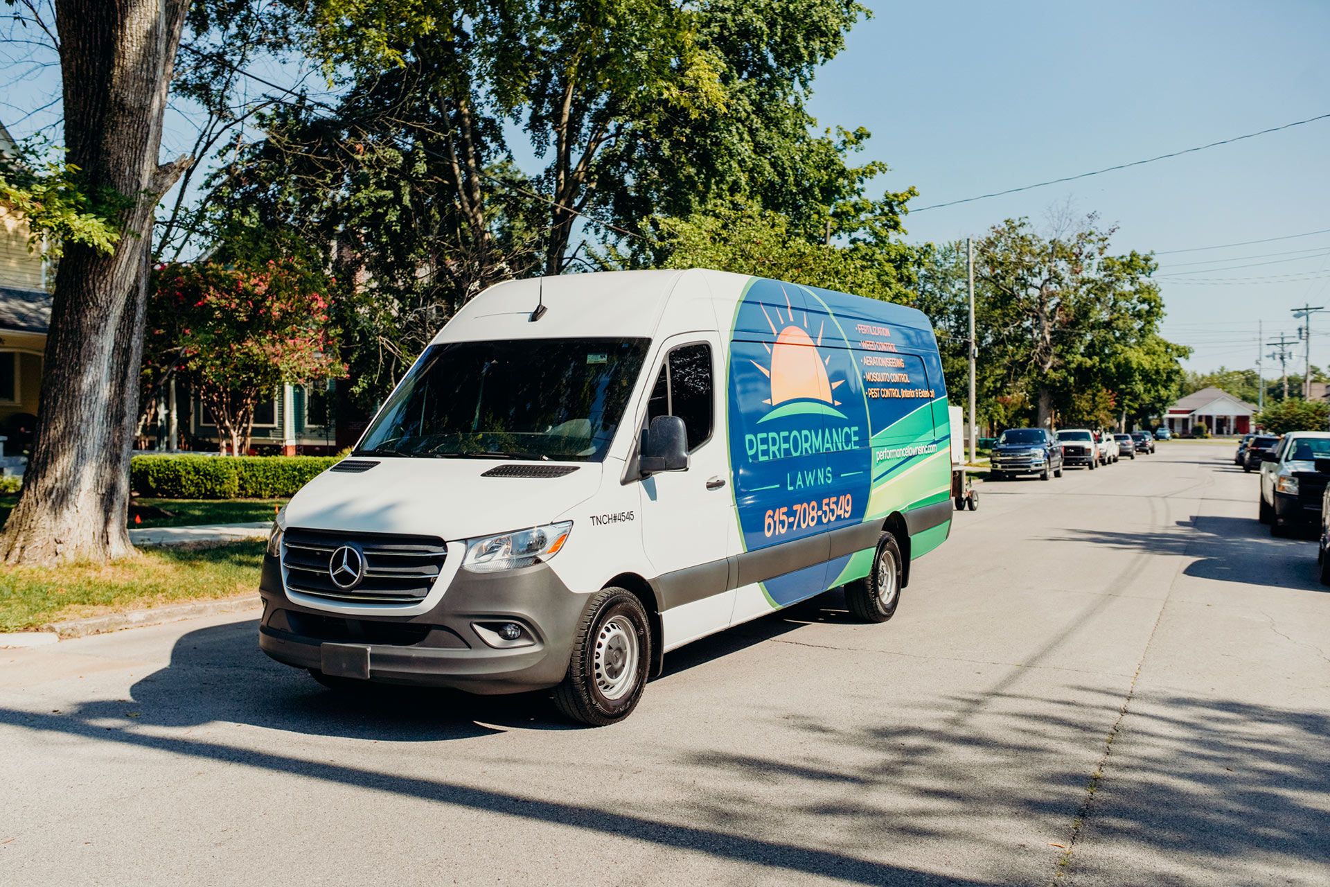 White and blue service van with company logo parked on a residential street.