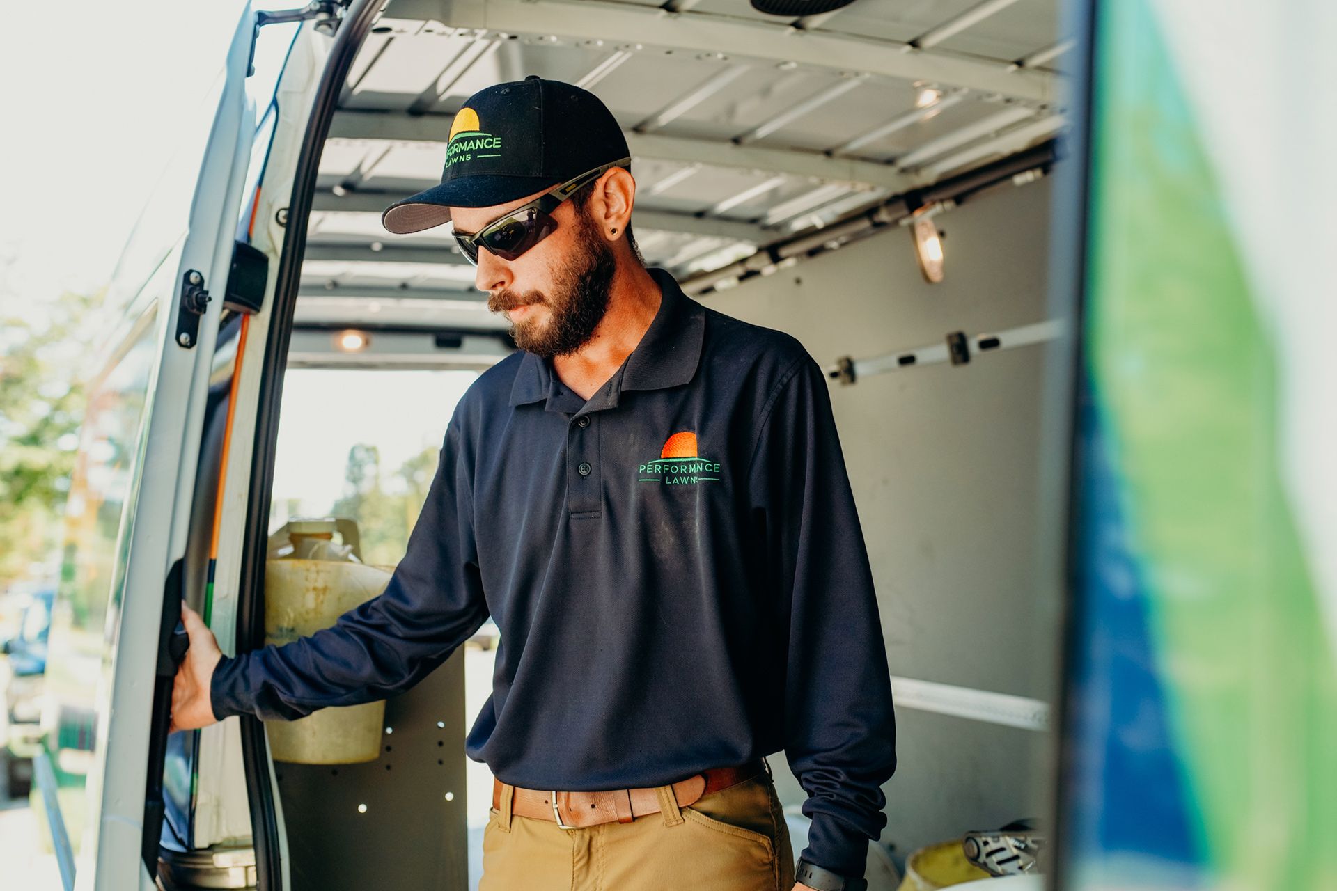 Man in uniform, sunglasses, opens van door. Inside is an organized workspace.