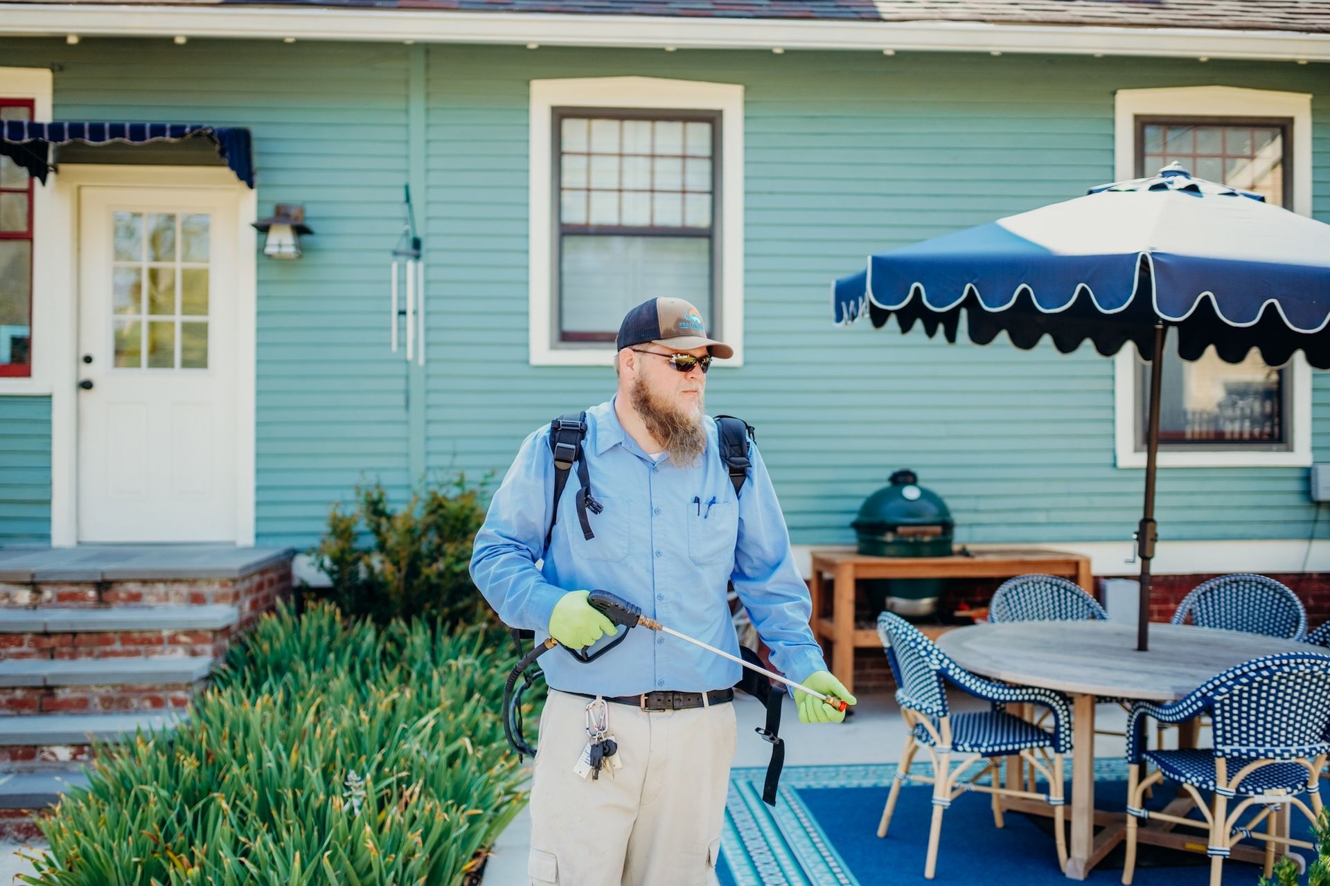 Man spraying a yard for pests; house in the background.