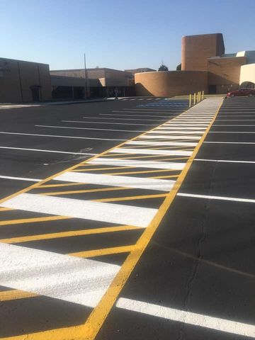 Empty parking lot with freshly painted white lines and a light post, under a blue sky.