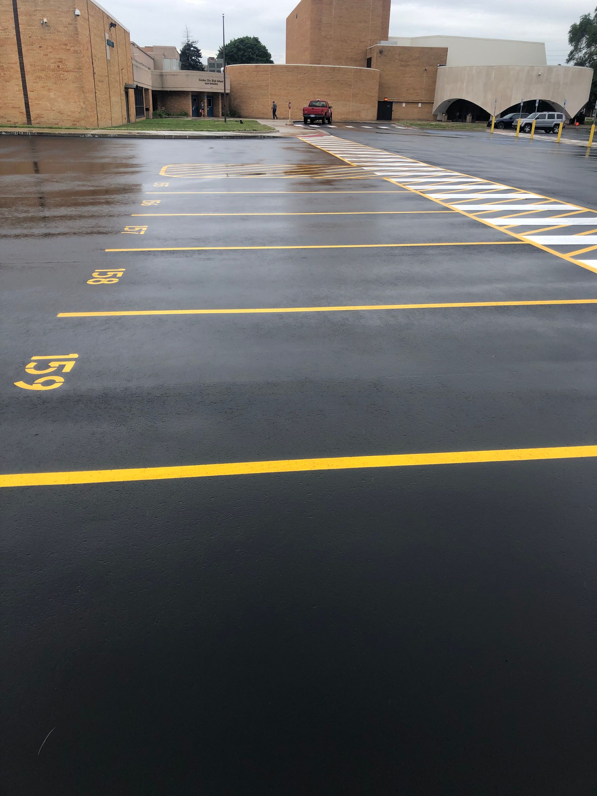 Freshly paved parking lot with yellow painted parking space lines and numbers.