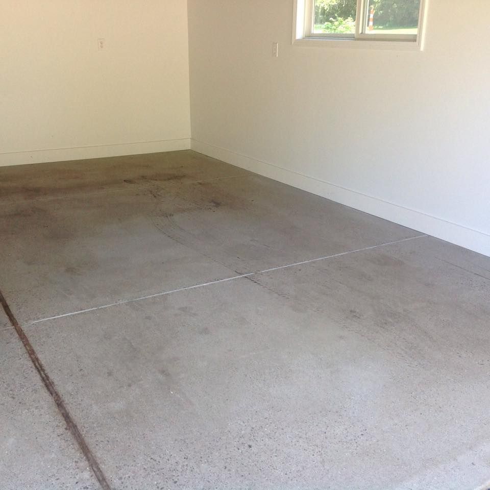 Concrete garage floor with white walls and a window.
