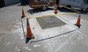 Orange traffic cone in a road excavation. Asphalt and wet surface.