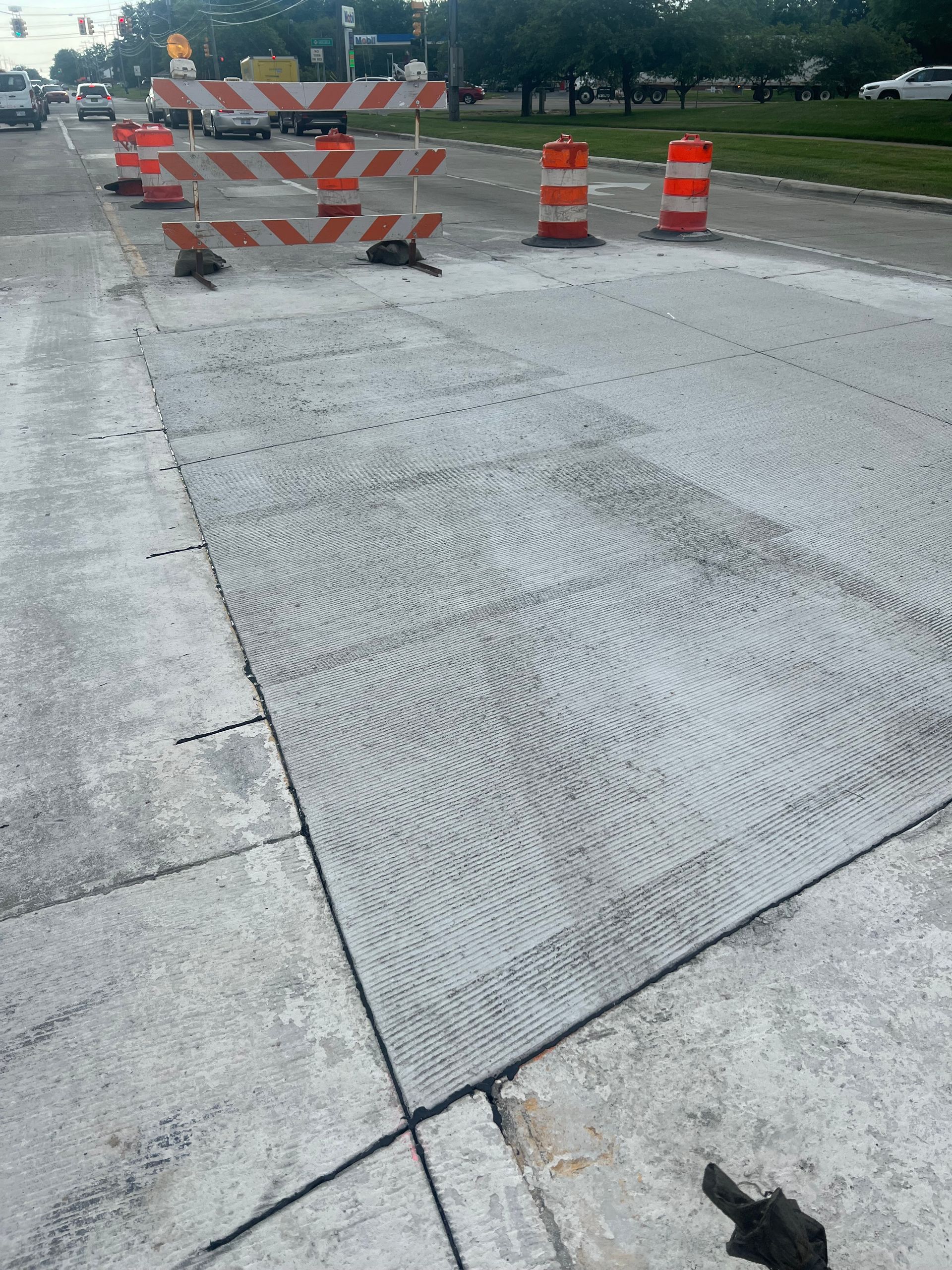 Road construction area with orange-and-white barricades on a concrete roadway.