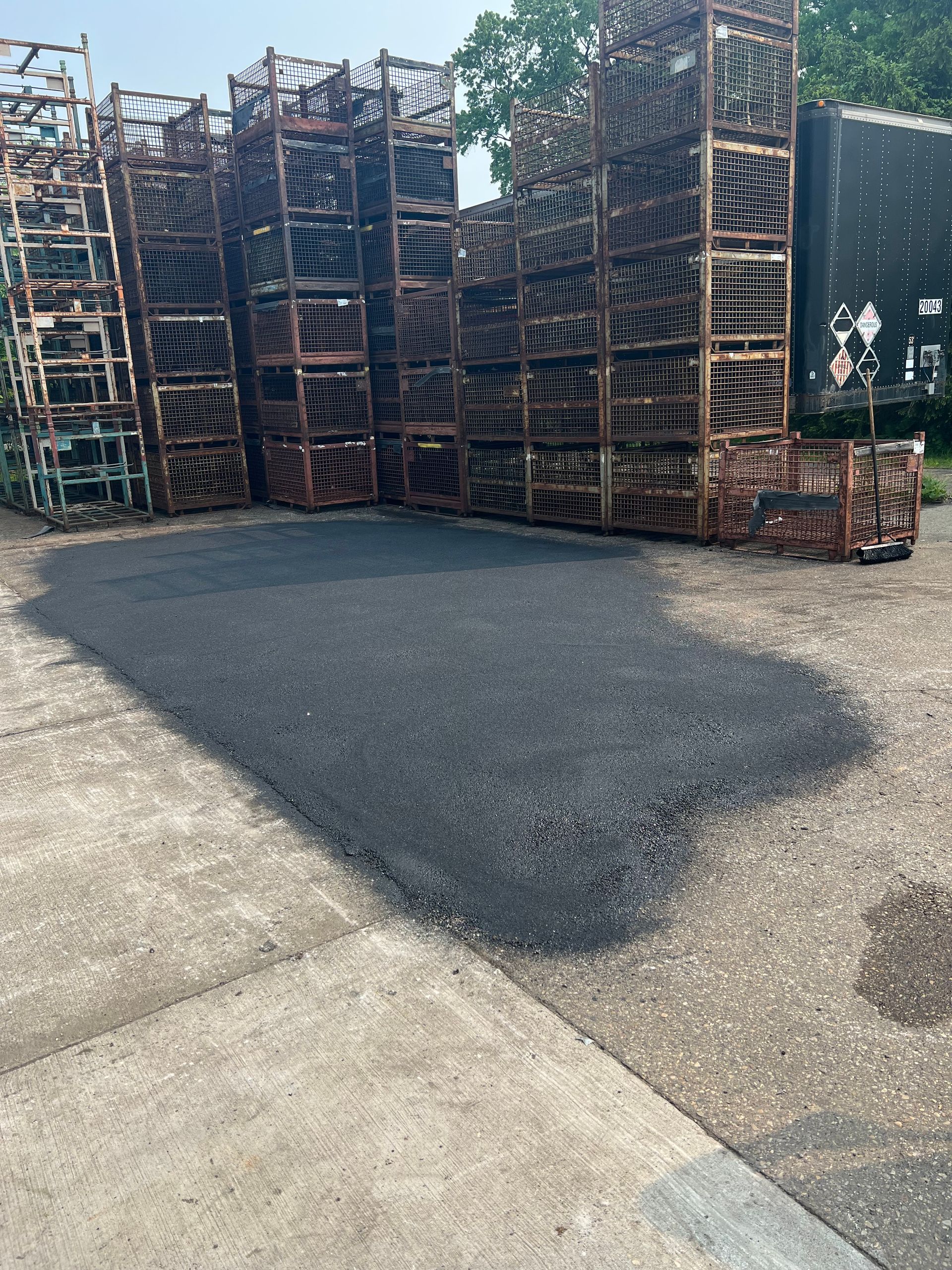 Stacks of metal crates and bins in an industrial yard beside a paved surface