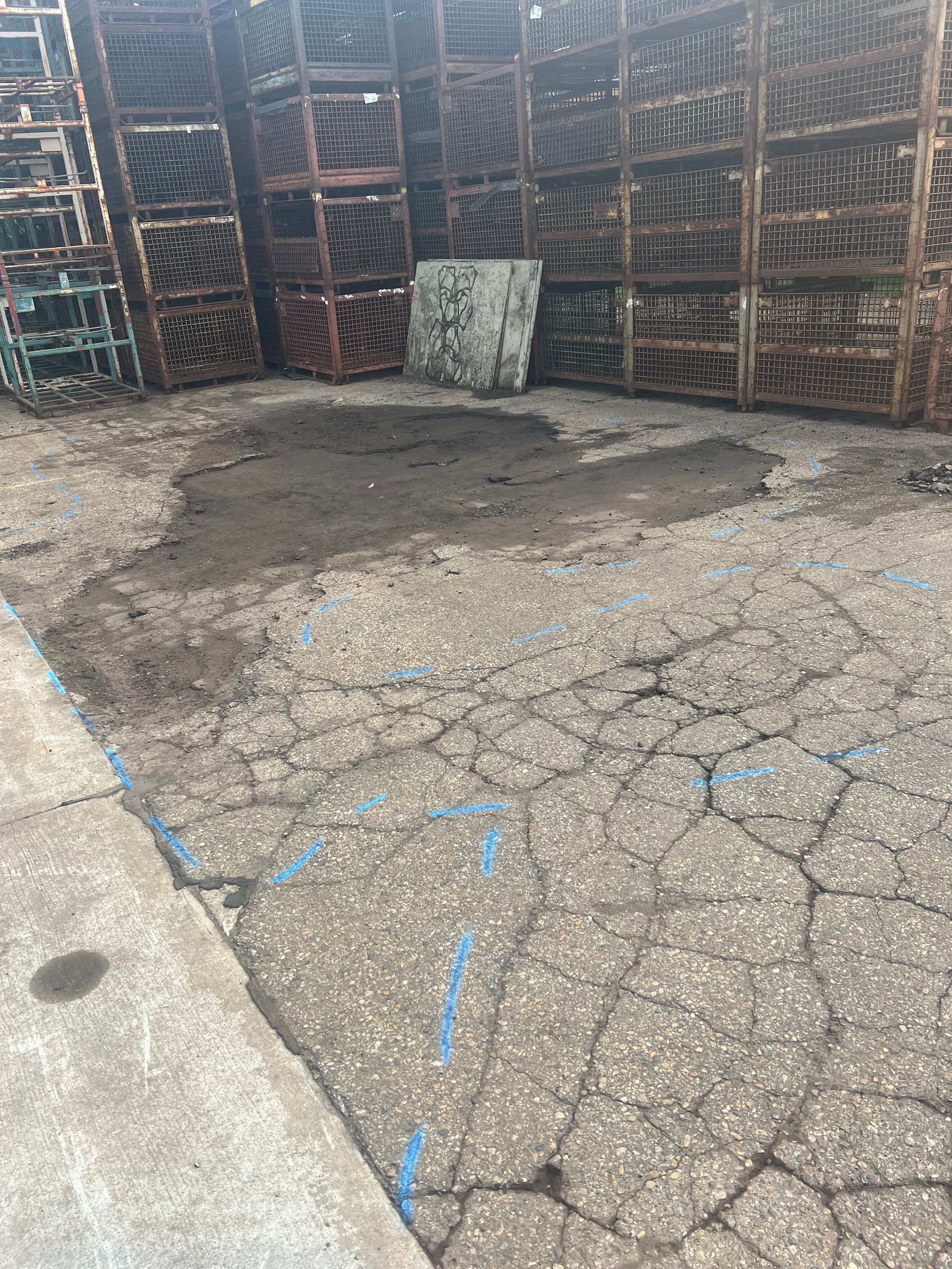 Cracked concrete floor in a storage area with wooden racks and a stained patch near the back wall