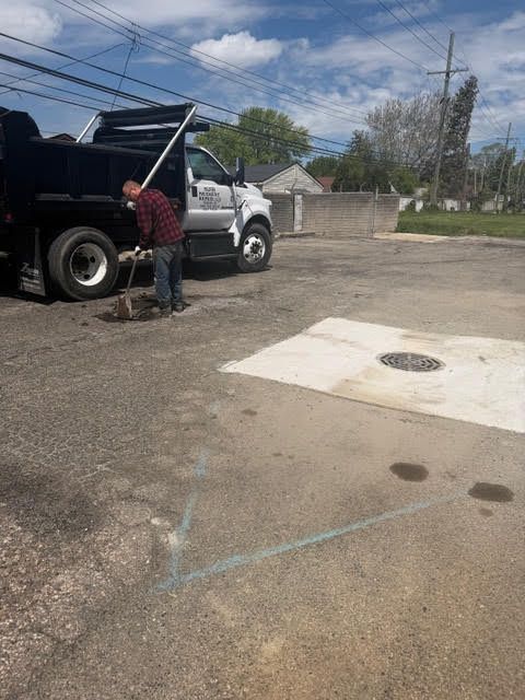 Worker unloading equipment from a black truck in a parking lot on a cloudy day