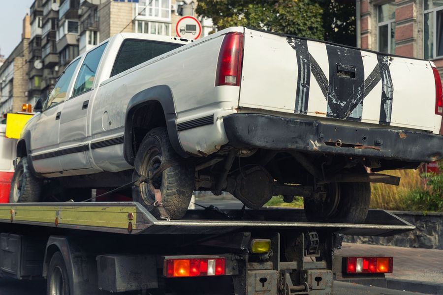 White pickup truck strapped on a tow truck in a city street during winter.