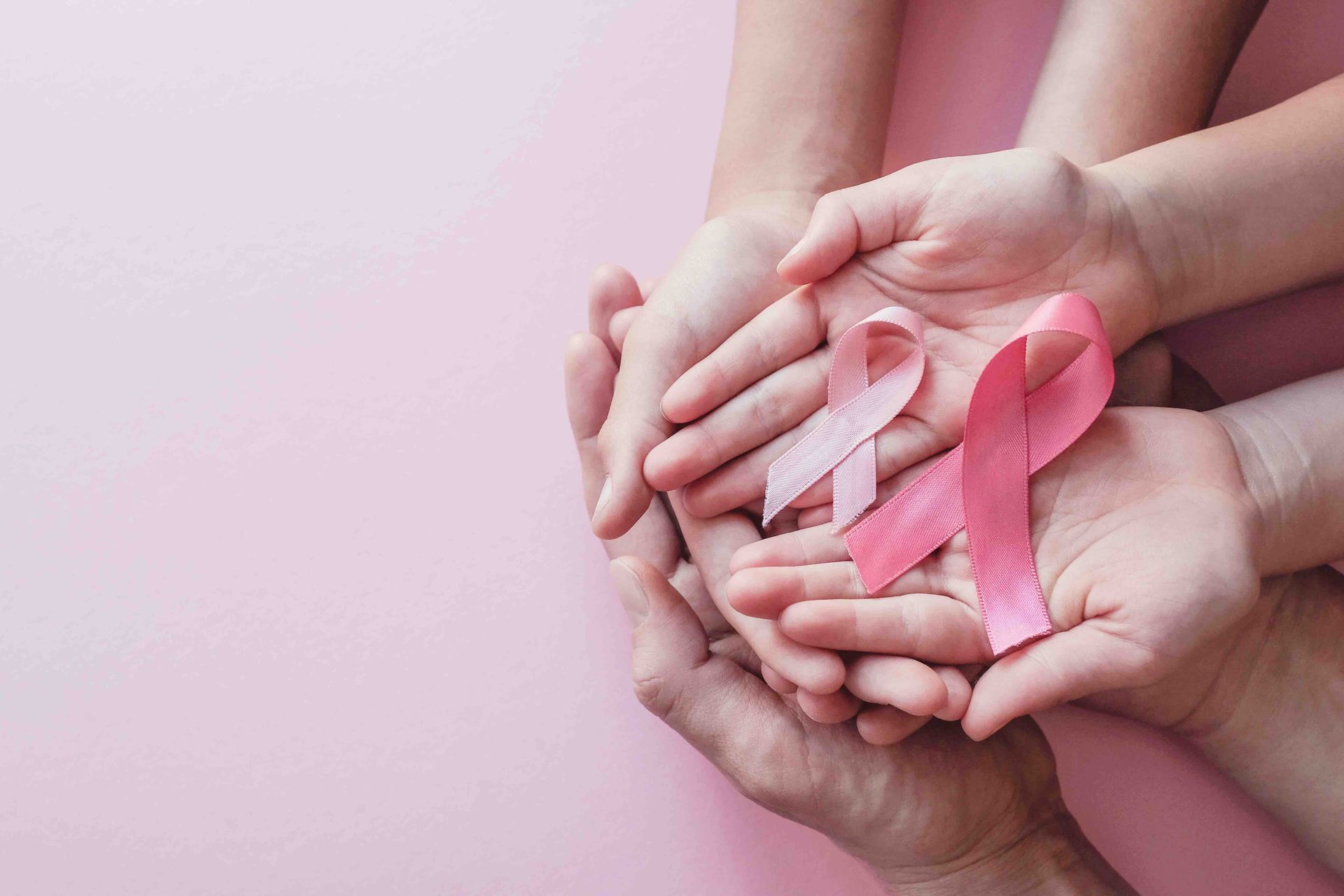 A group of people are holding pink ribbons in their hands.