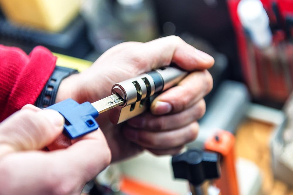 A Close up Of a Person Holding a Key and A Lock Cylinder — Century Locksmiths In Warwick, QLD