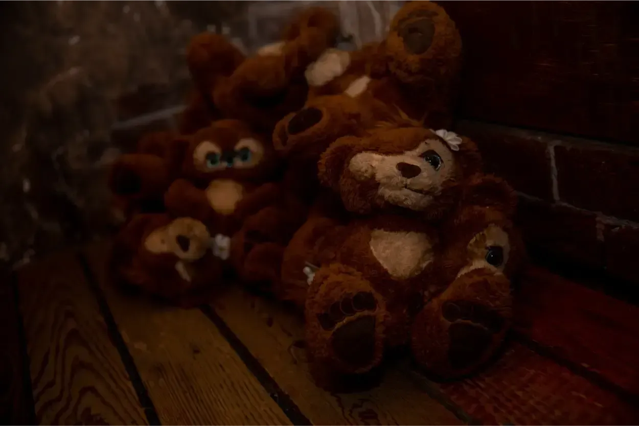 Een groepje teddyberen zit op een houten vloer.
