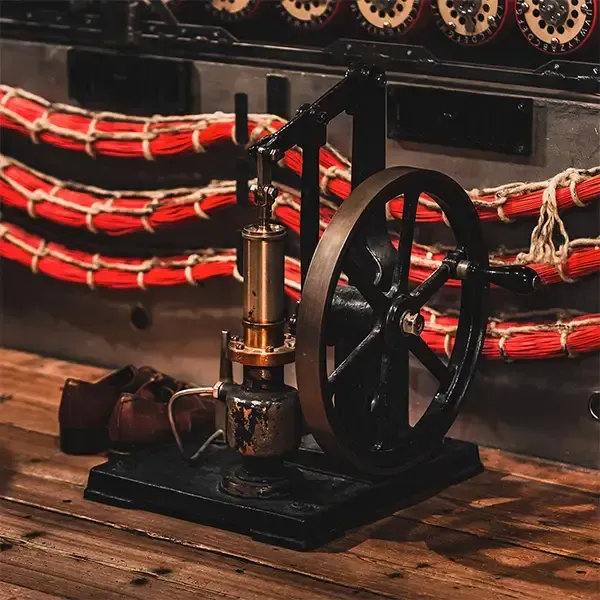 Een kleine stoommotor staat op een houten tafel