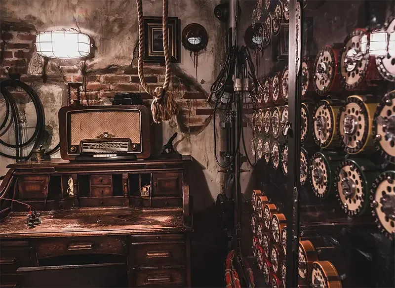 De imitation room met een bureau, radio, klokken en een bakstenen muur.