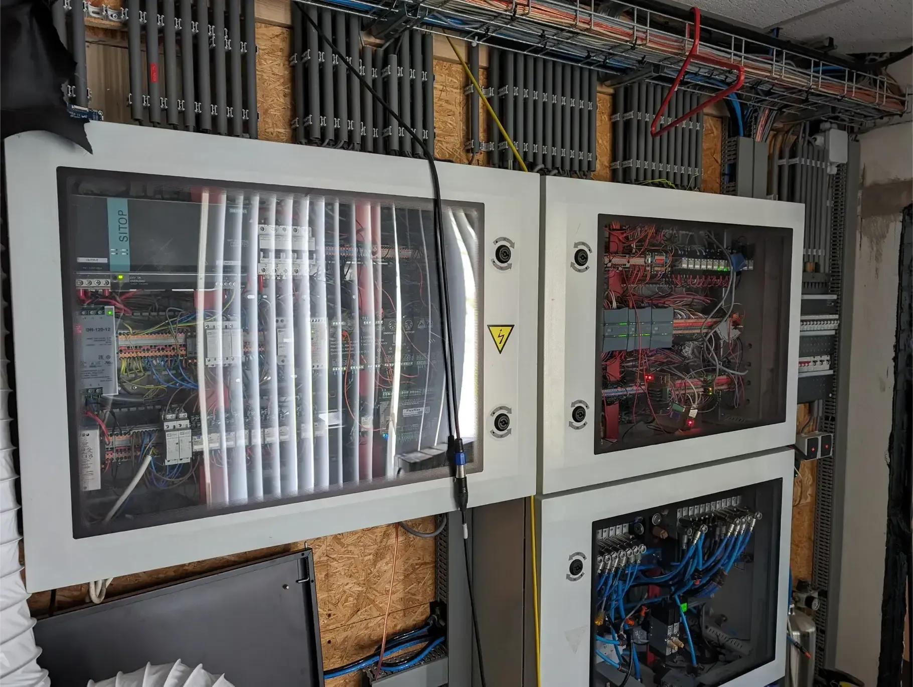 Een aantal elektrische dozen zijn op elkaar gestapeld tegen een muur.