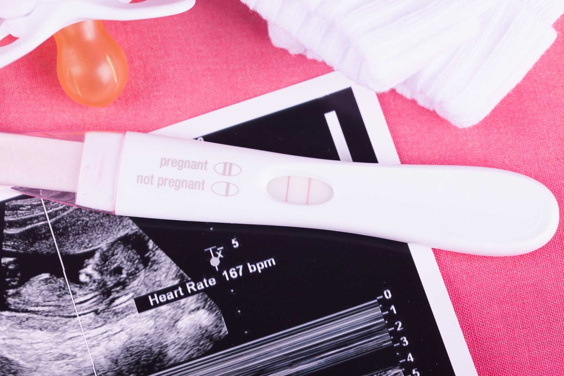 Ultrasound photo and pregnancy test with a pink background. Ultrasound photo and pregnancy test with a pink background.