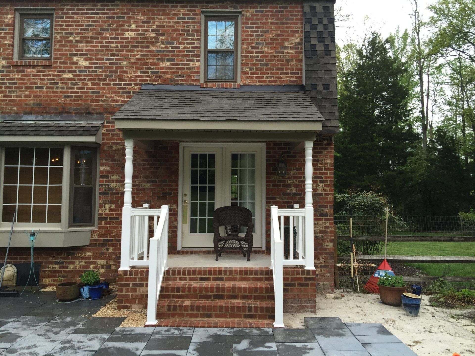 White porch railings and stair handrails framing the entry to a brick home.