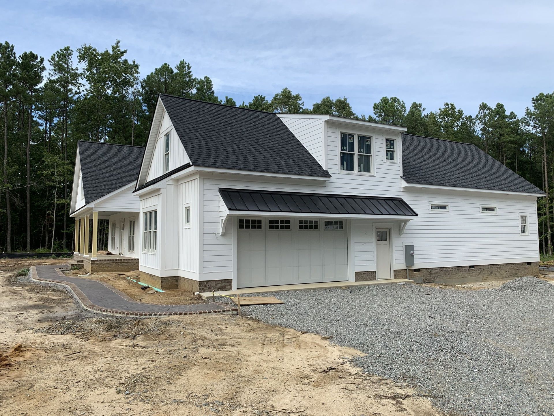 White house with dark shingle roofing and metal accent roof above garage