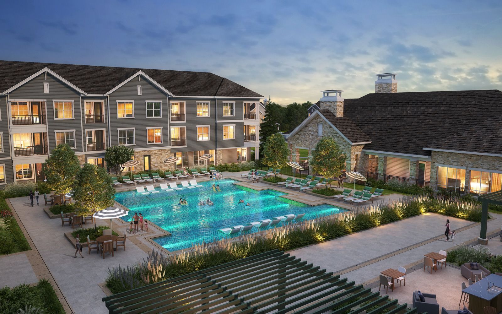 Apartment complex with a pool and a stone clubhouse at dusk.