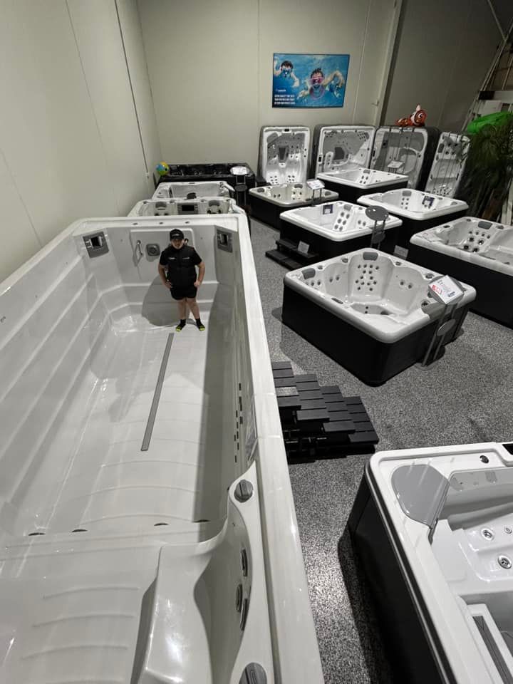 A man is standing in a room filled with lots of hot tubs.