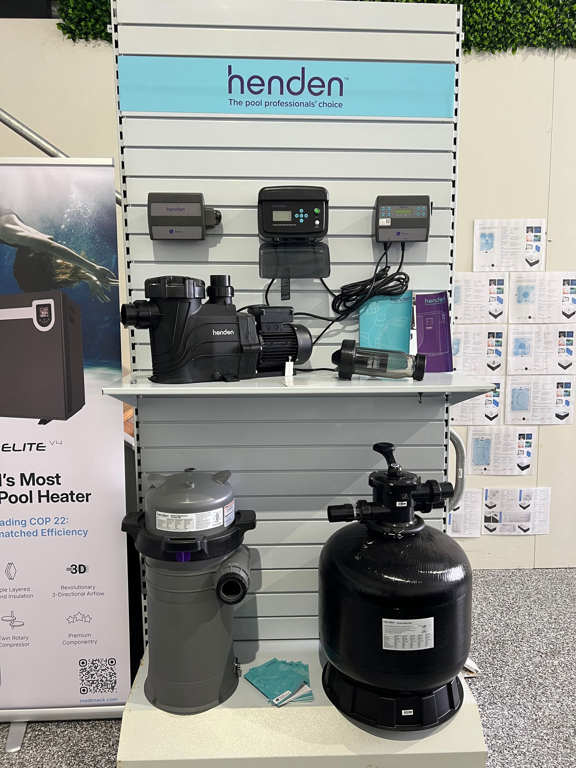 Display wall with Henden pool equipment, pumps, and filters on shelves in a store.