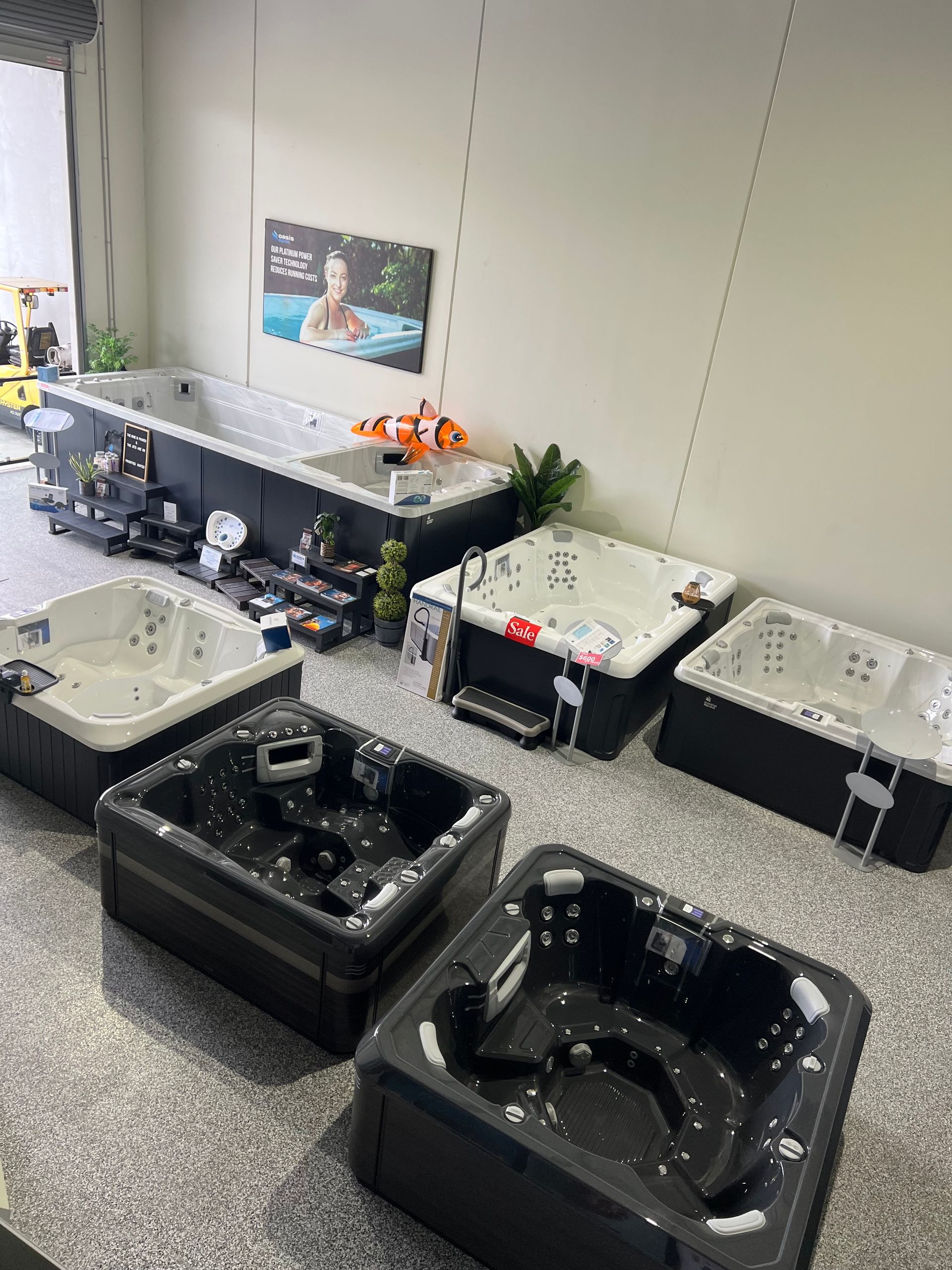 Row of black and white pet grooming tubs along a wall in a tiled grooming room