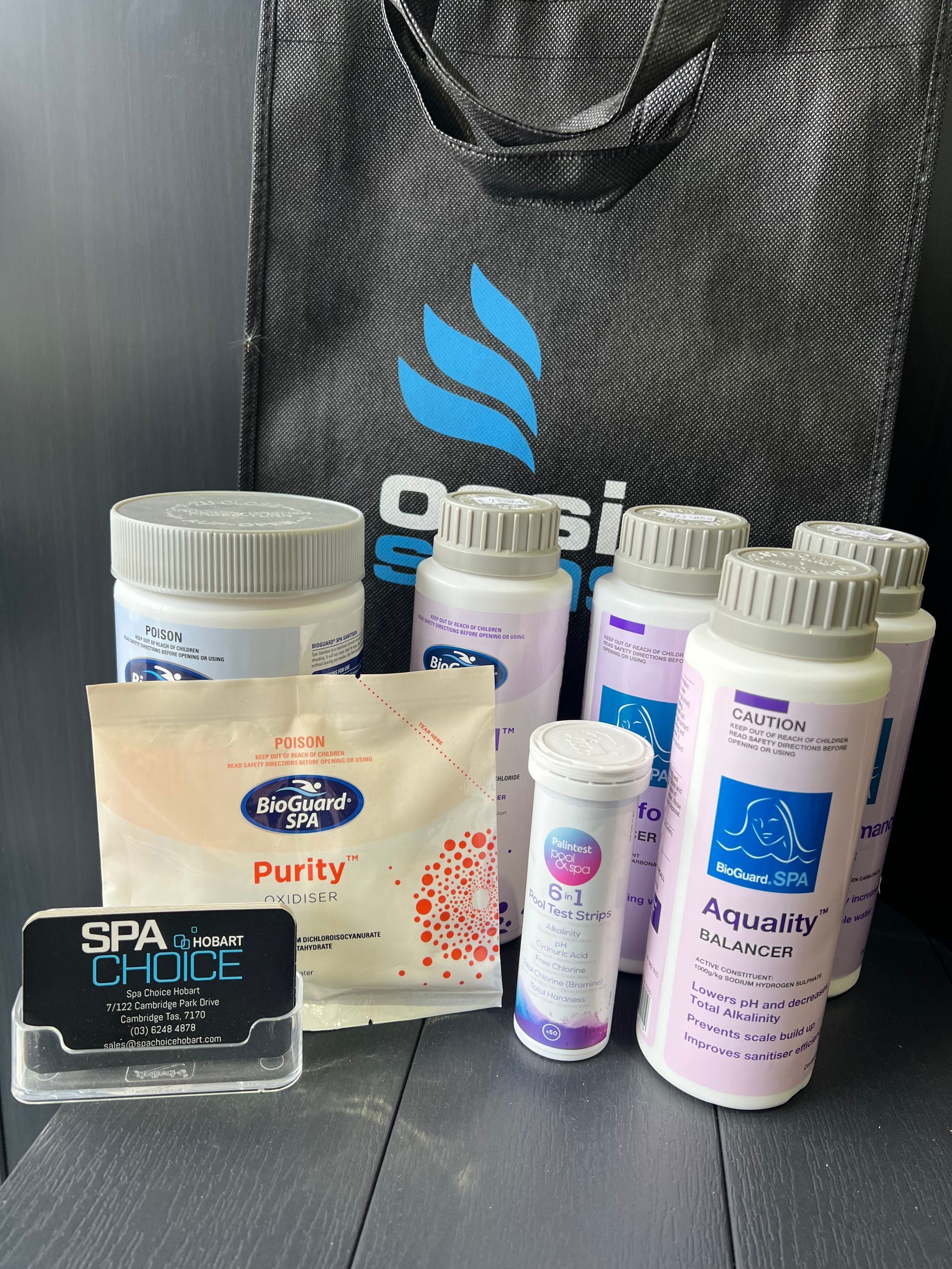 Assorted skincare and bath products displayed on a counter with a black shopping bag in the background