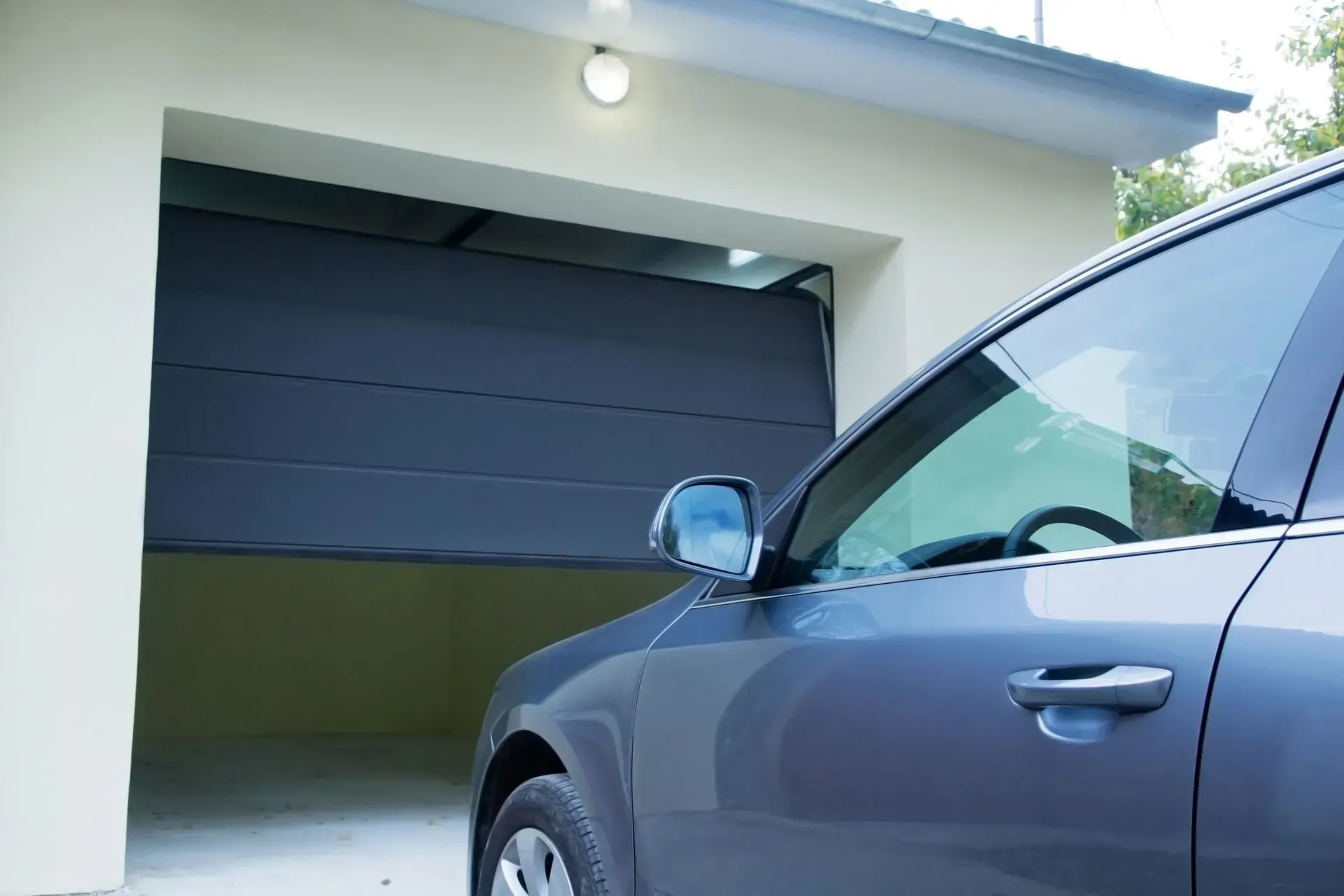 A blue car is parked in a garage with the door open.