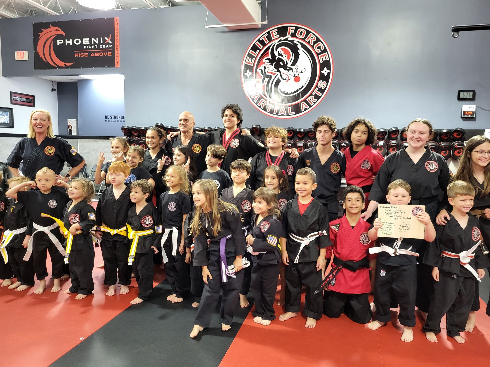A group of kids are posing for a picture in front of a sign that says phoenix martial arts