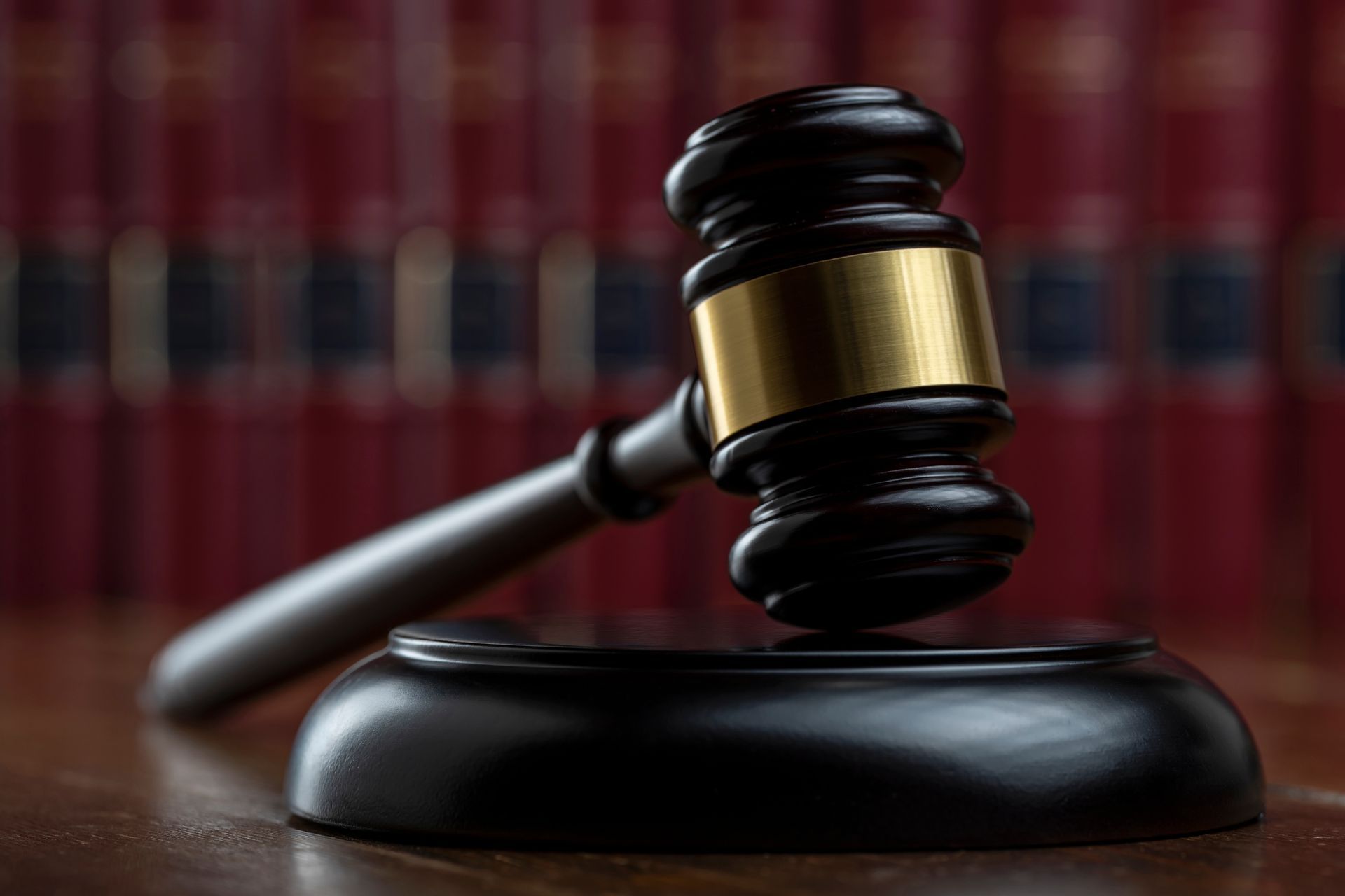 Wooden gavel on a stand; red law books in background.