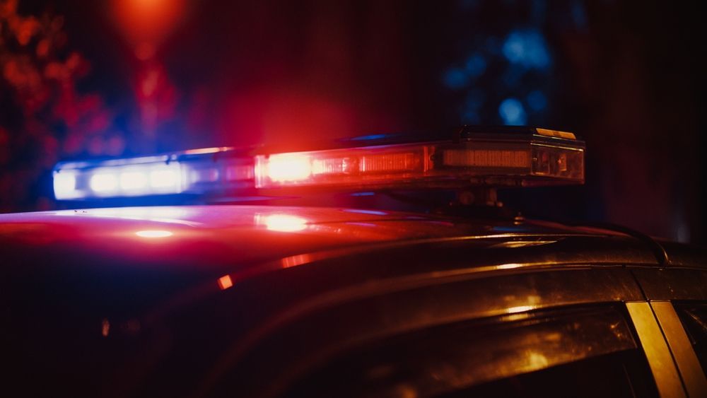 Police car with flashing red and blue lights at night.