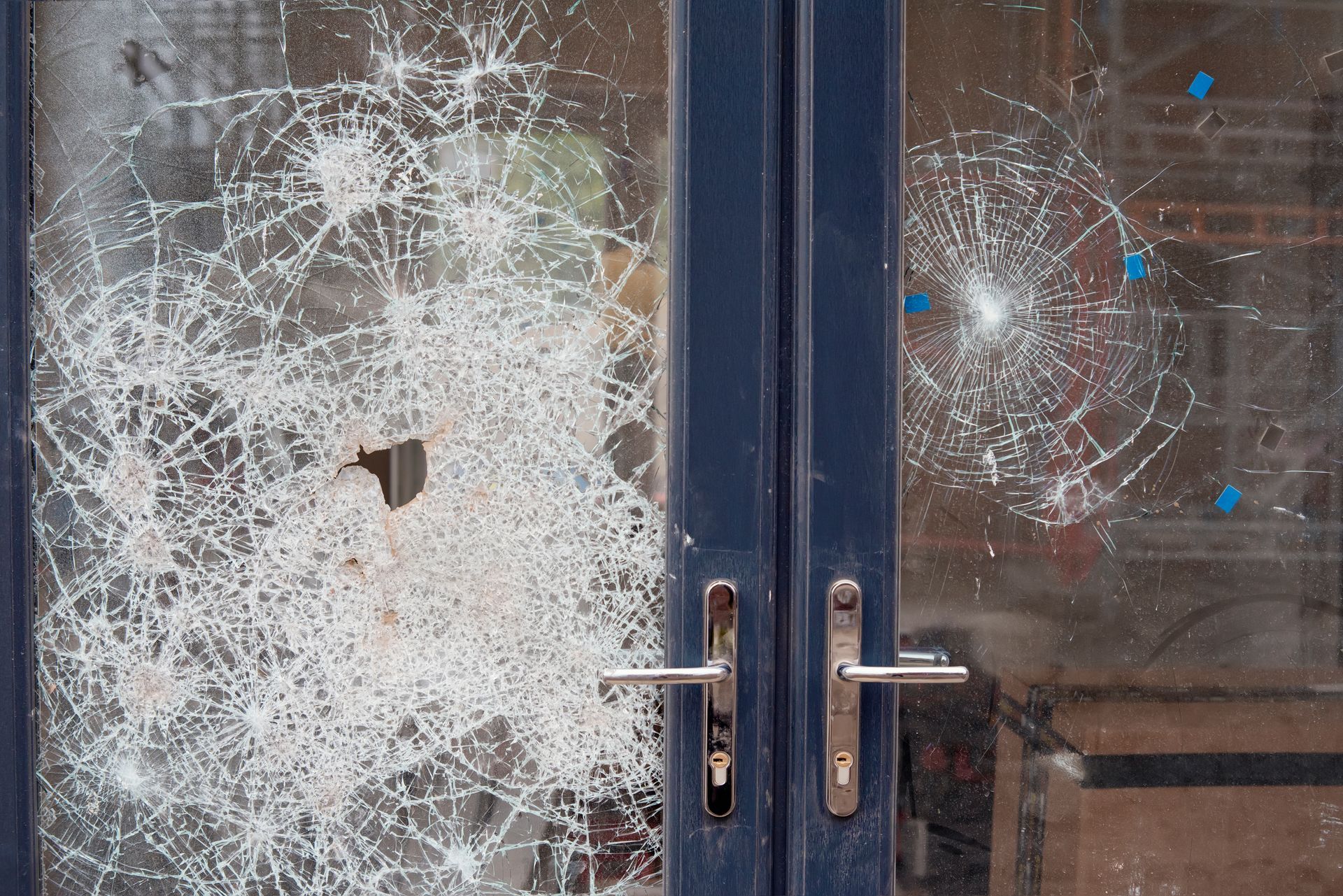 Broken glass doors with shattered sections. Dark blue door frame and handles.