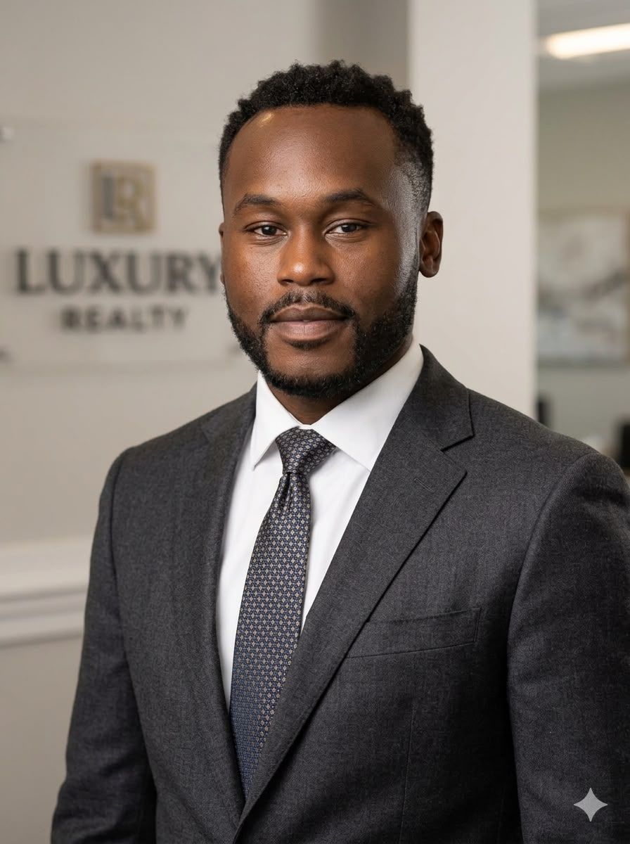 Man in a dark suit and tie standing in an office lobby with a luxury real estate sign behind him