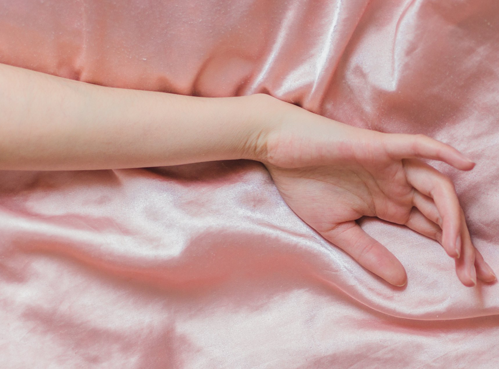 hand relaxing on pink satin