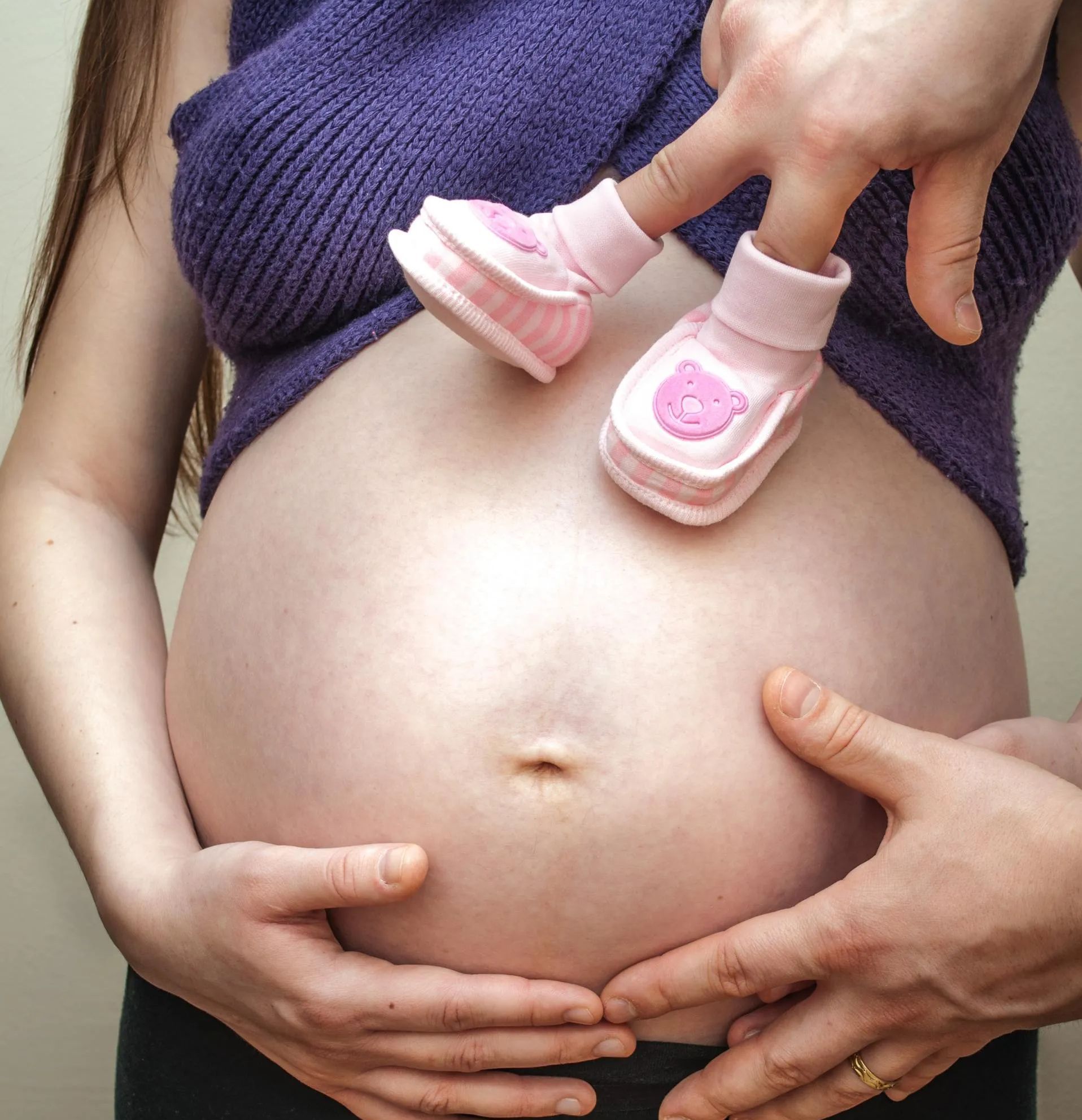 pregnant belly with tiny shoes walking on it