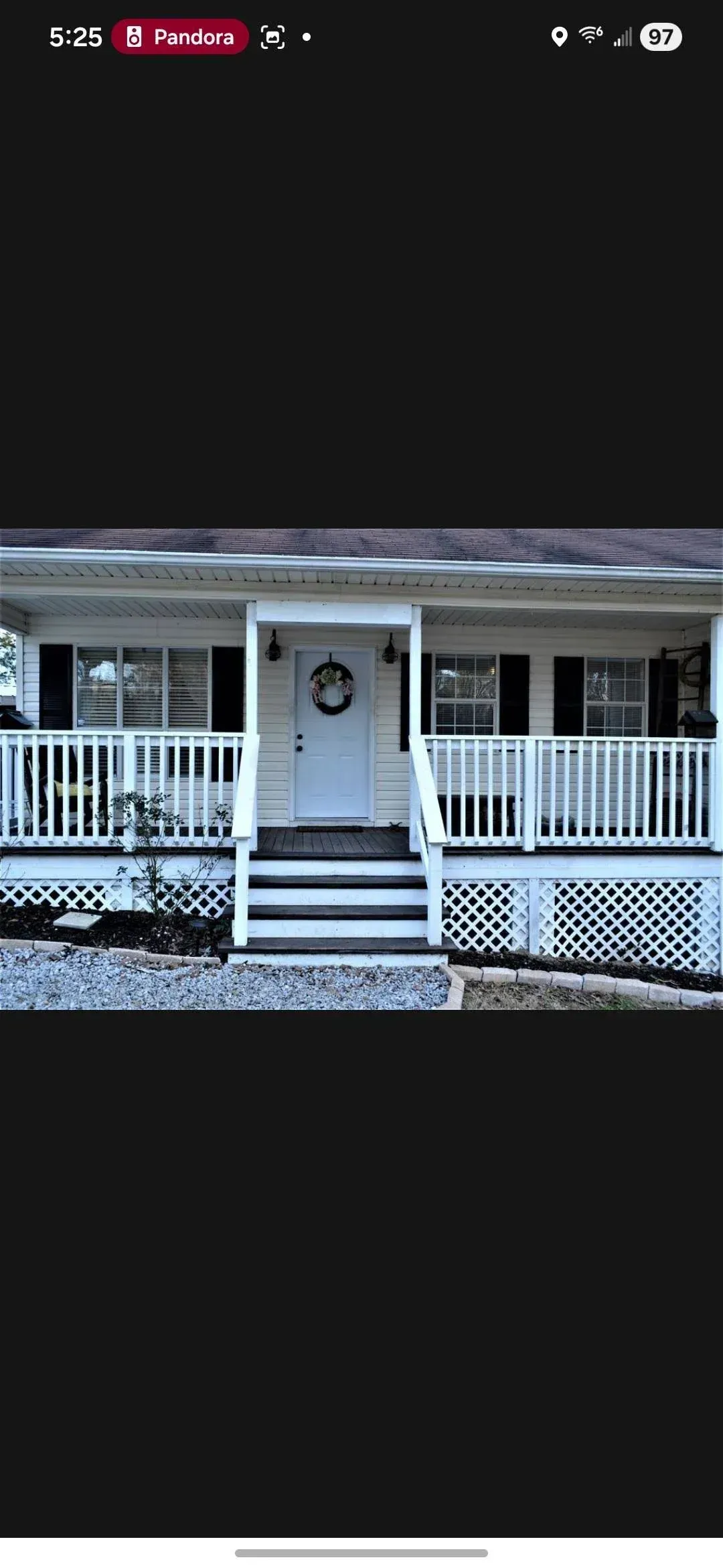 Front porch of a white house with a centered front door, railing, and steps under a dark roofline.