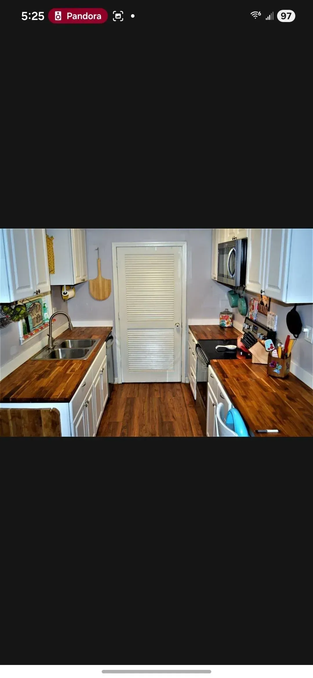 Narrow galley kitchen with wooden cabinets, white appliances, and a light rug on the floor.