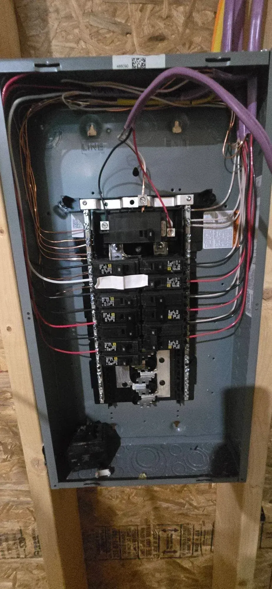 Open electrical breaker panel with exposed wiring and circuit breakers in a metal box.
