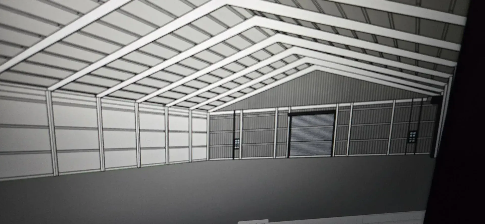 Empty metal warehouse interior with exposed truss roof and corrugated walls