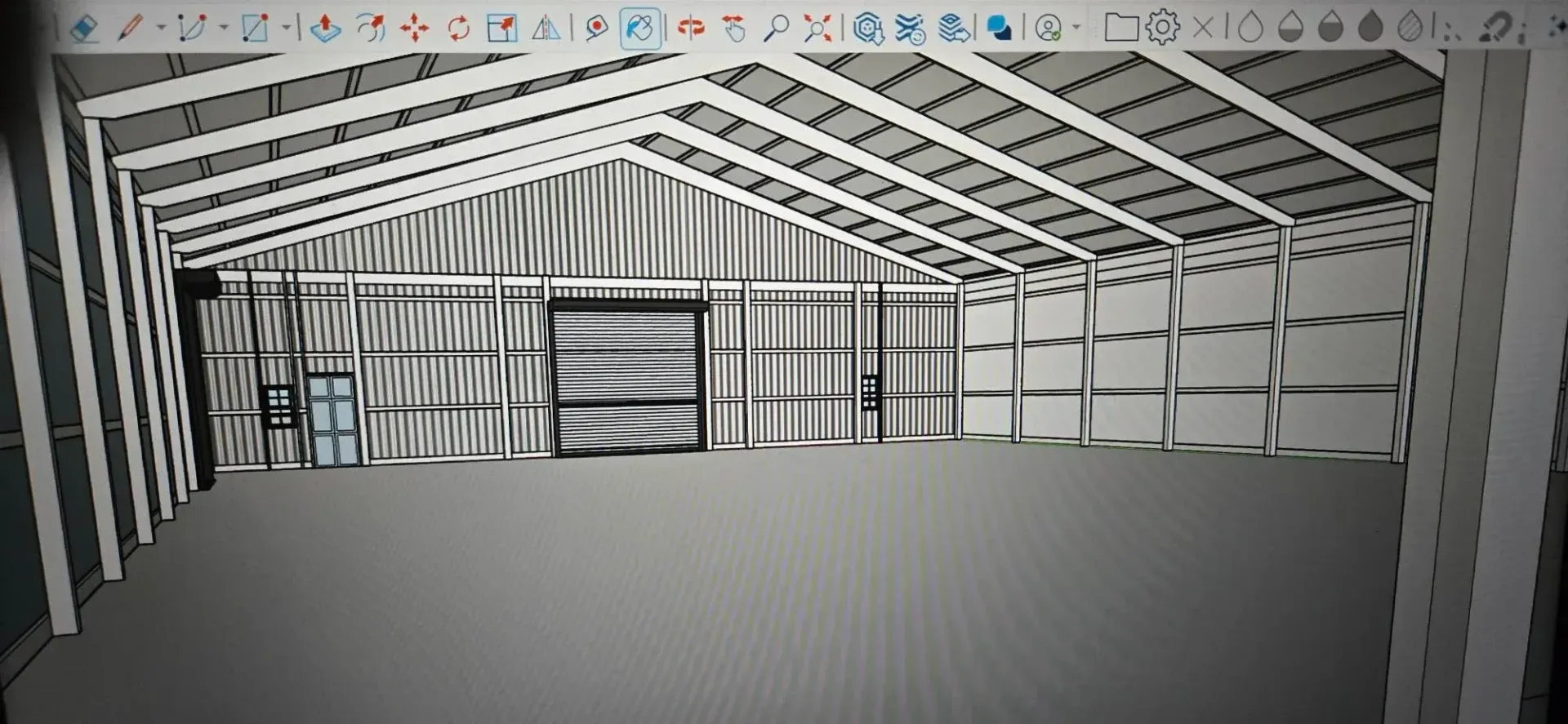 Interior of a steel-framed warehouse under construction with open wall and roof trusses