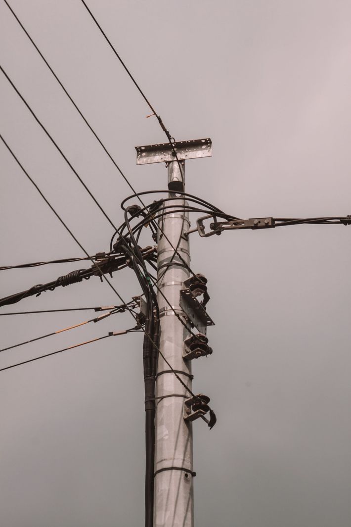 Utility pole with tangled power lines and transformer against a gray sky