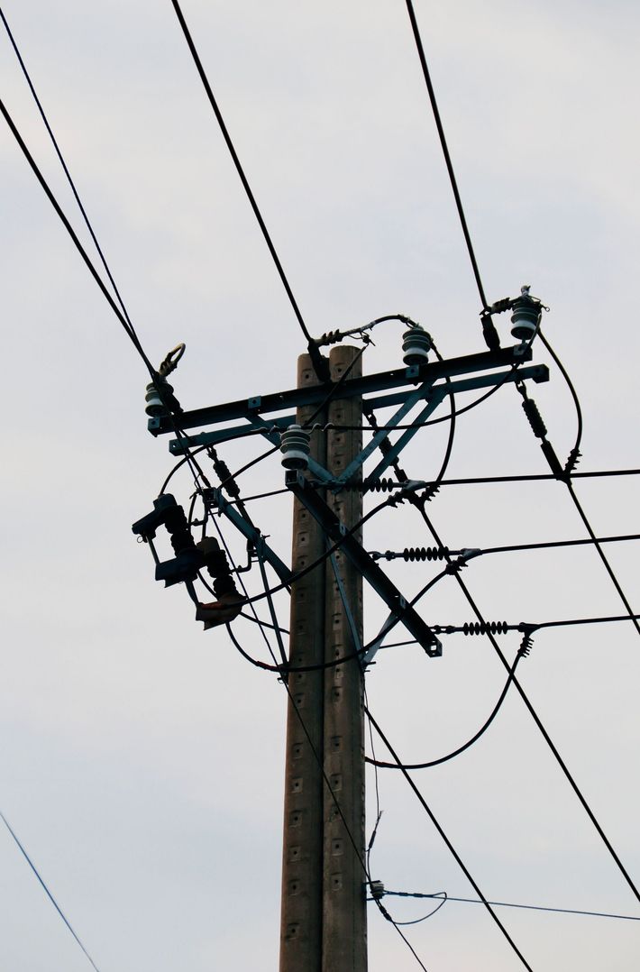 Utility pole with power lines and electrical equipment against a cloudy sky