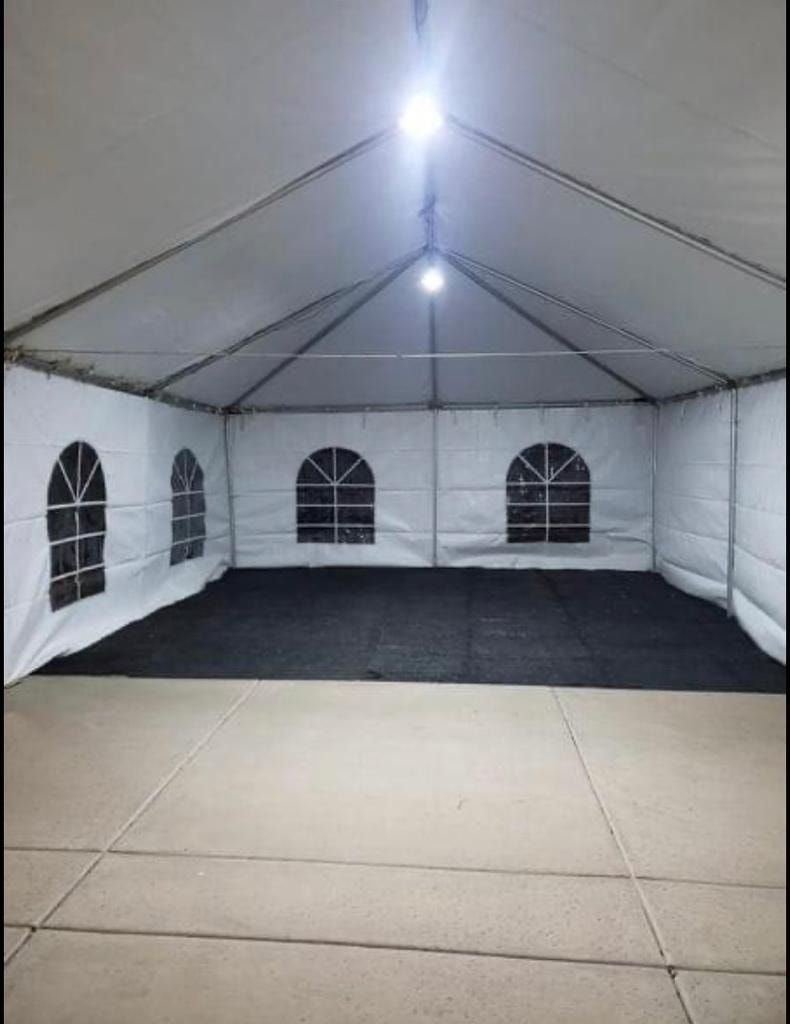 An indoor view of a white tent with arched windows and a black floor, set up on a concrete patio.