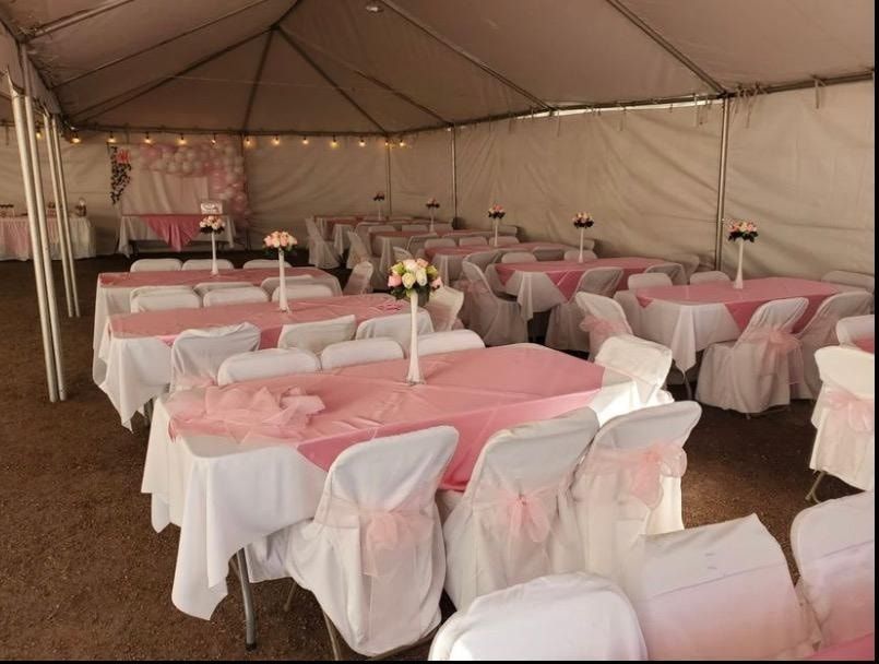 Rows of tables covered in white and pink cloths under a large white event tent, decorated with floral centerpieces.