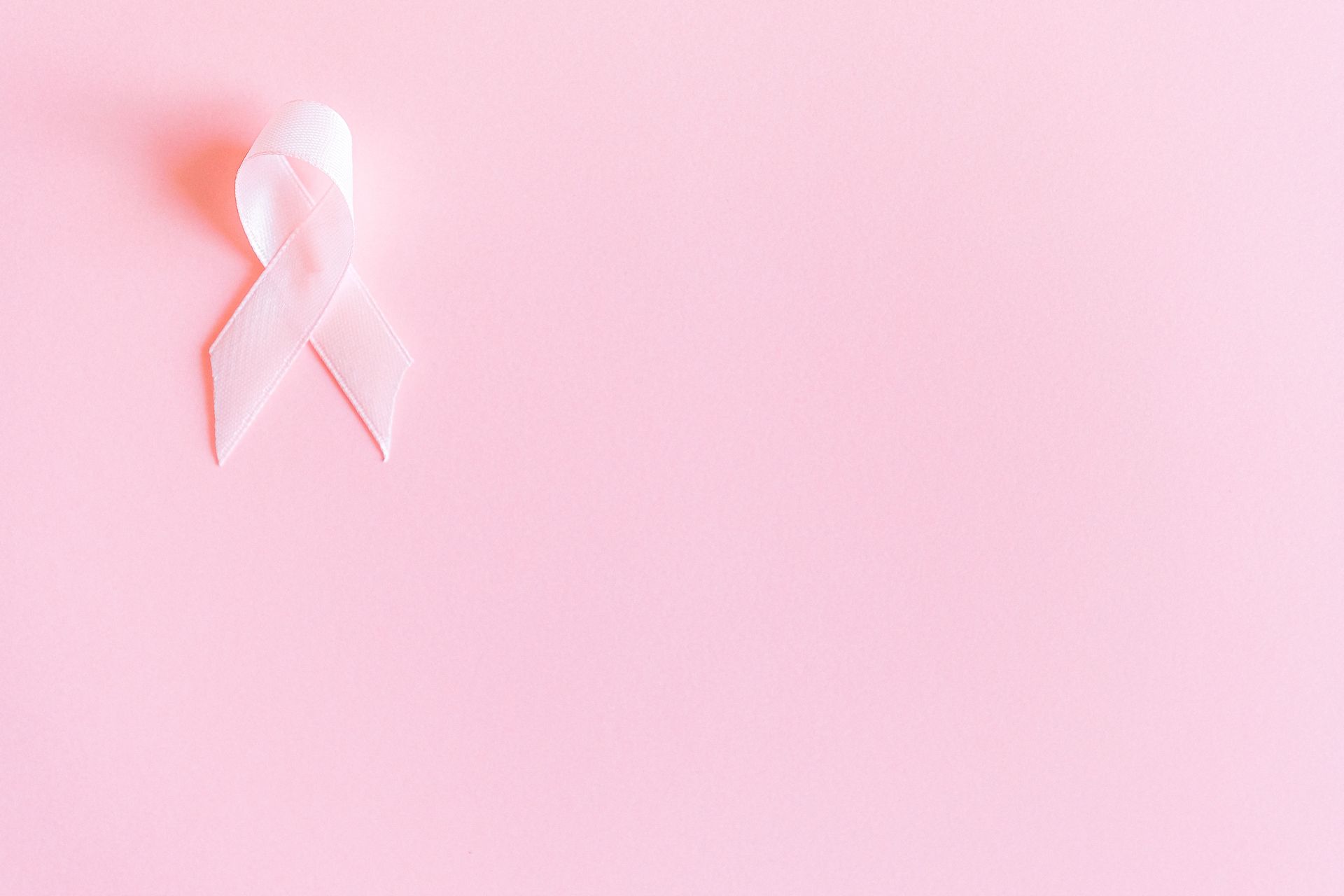 Pink awareness ribbon on a soft pink background