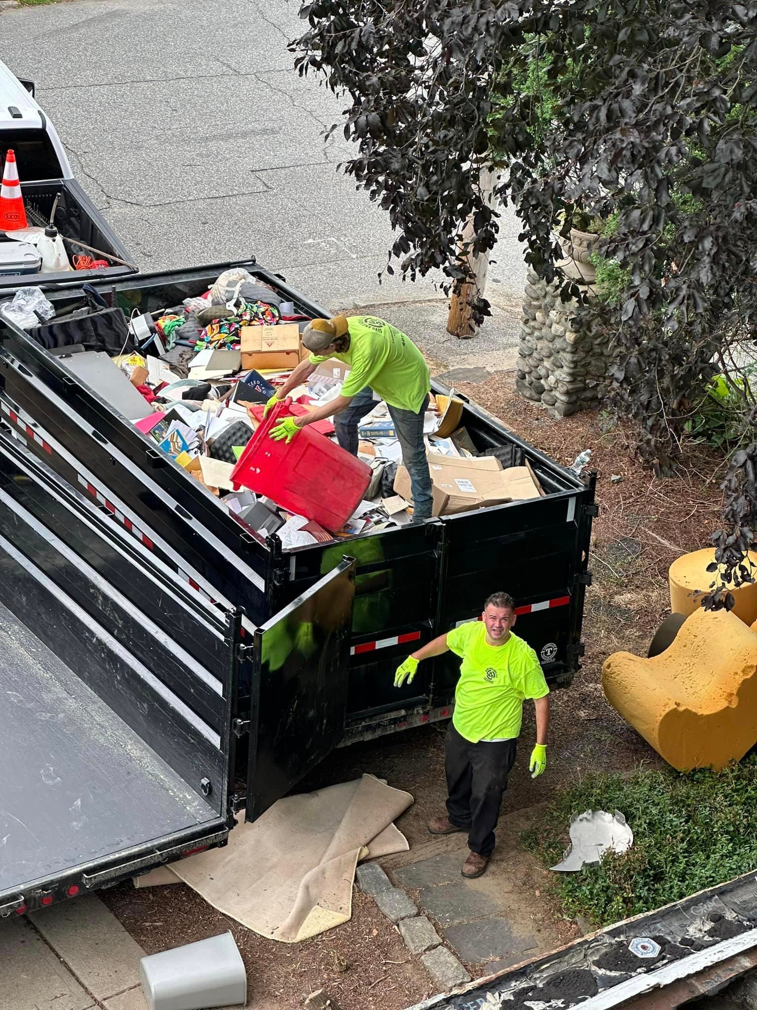 A man is standing next to a dumpster filled with trash.