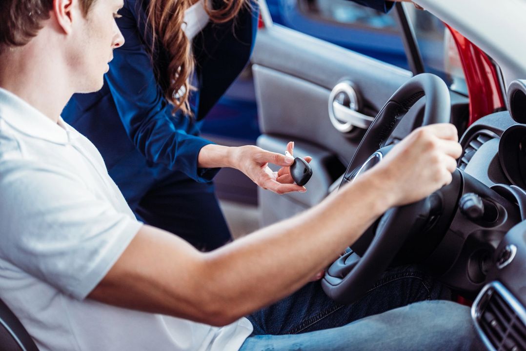 Pilota e istruttore all'interno di un'auto rossa, si esercitano con il cambio manuale.